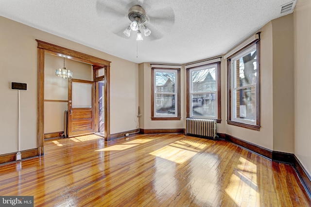 unfurnished room featuring light wood-type flooring, visible vents, baseboards, and radiator