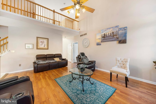 living room featuring ceiling fan, a towering ceiling, and hardwood / wood-style flooring