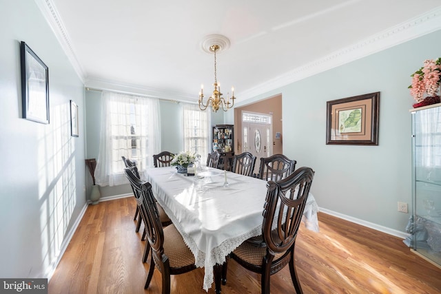 dining area featuring light hardwood / wood-style flooring, crown molding, and an inviting chandelier