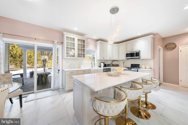 kitchen featuring a breakfast bar, white cabinets, decorative light fixtures, a kitchen island, and stainless steel appliances