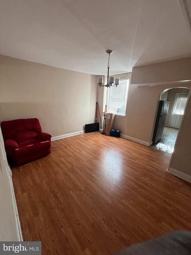 unfurnished living room with hardwood / wood-style flooring and a notable chandelier