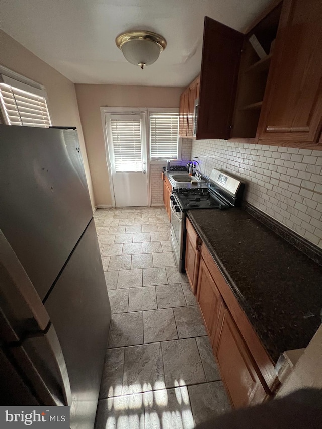 kitchen featuring tasteful backsplash, dark stone counters, sink, and stainless steel appliances