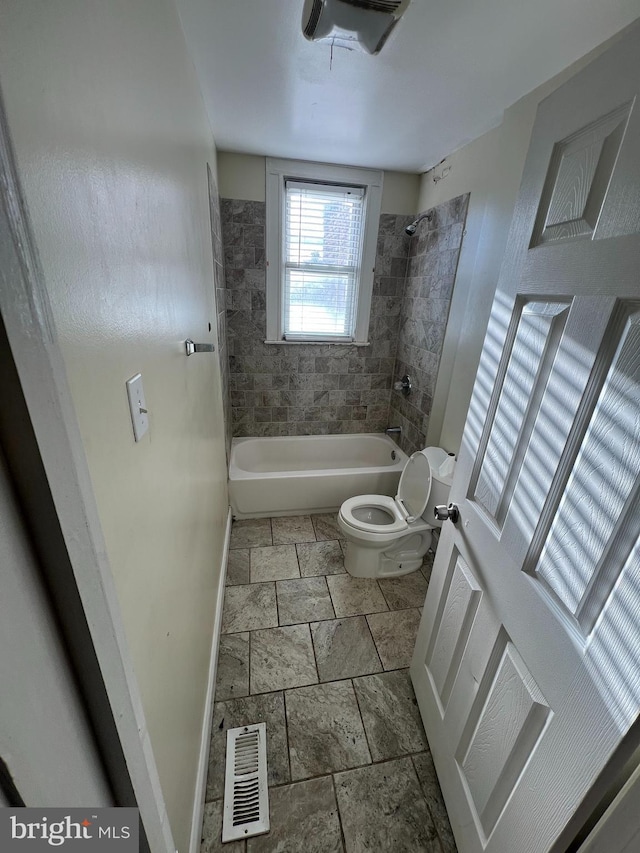 bathroom with tiled shower / bath combo and toilet