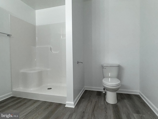 bathroom with baseboards, toilet, walk in shower, and wood finished floors