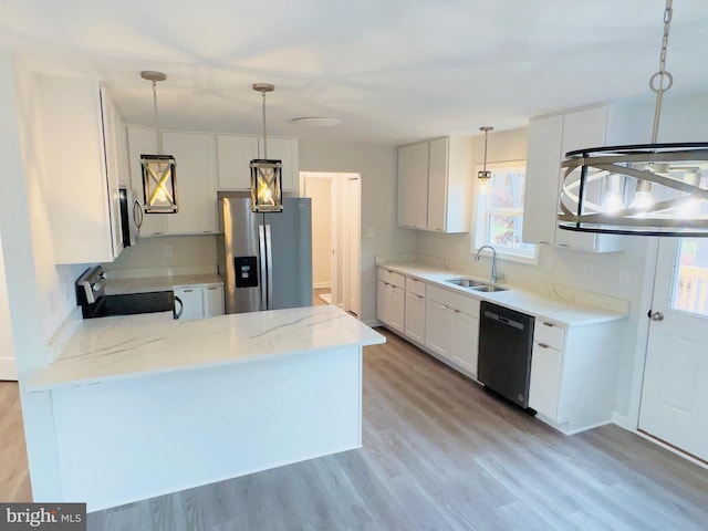 kitchen with a sink, light stone counters, decorative light fixtures, stainless steel appliances, and a peninsula