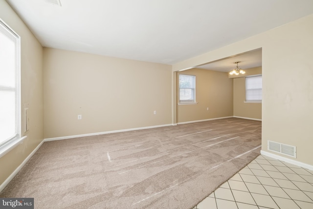 empty room with light carpet and a notable chandelier