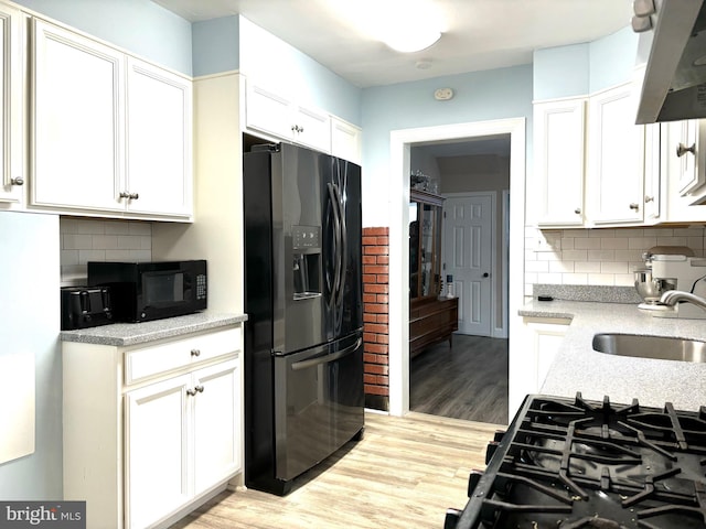 kitchen with white cabinetry, sink, tasteful backsplash, black appliances, and light wood-type flooring