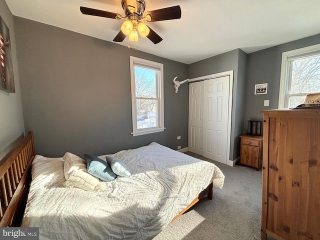 bedroom with multiple windows, a closet, ceiling fan, and light colored carpet