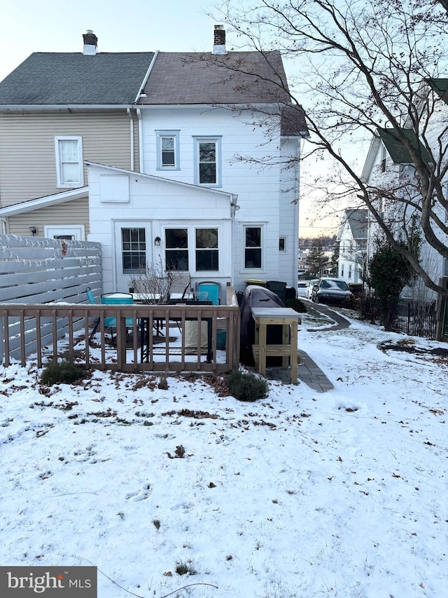 snow covered back of property with a deck