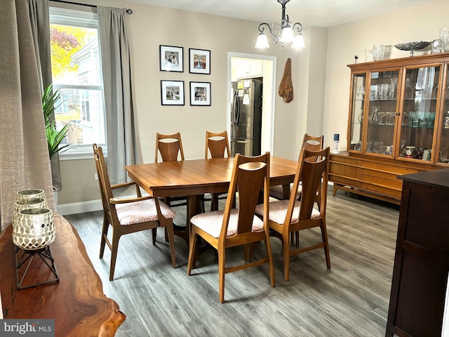 dining space with wood-type flooring and a notable chandelier