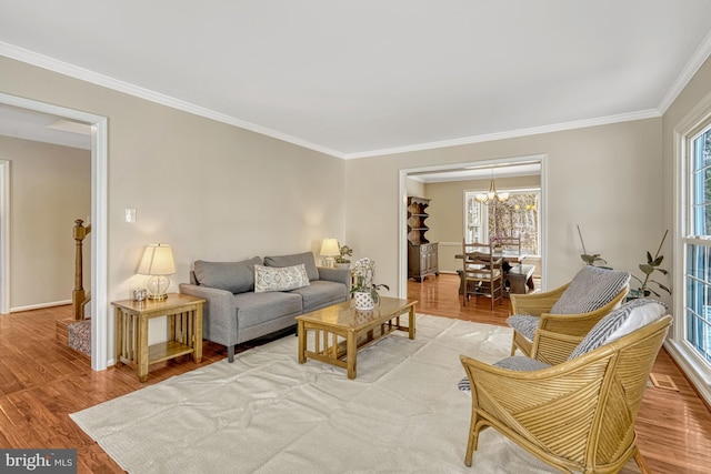 living room with crown molding, light hardwood / wood-style flooring, and a notable chandelier