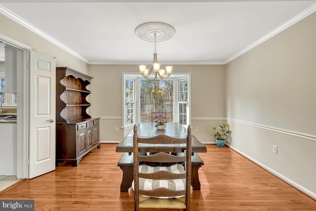 dining space with ornamental molding, a notable chandelier, and light wood-type flooring