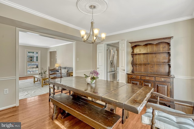 dining space featuring ornamental molding, a notable chandelier, and light wood-type flooring