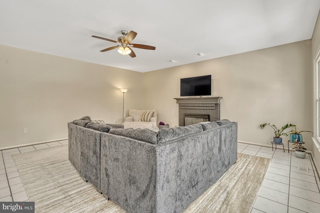 tiled living room with ceiling fan and a brick fireplace