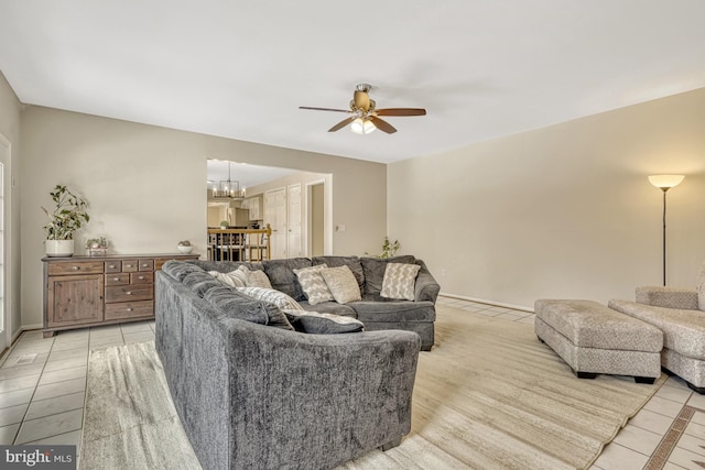 tiled living room with ceiling fan with notable chandelier