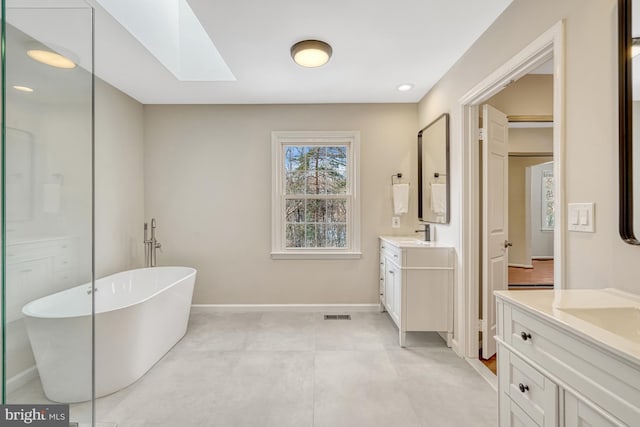 bathroom with a bathtub, vanity, and a skylight