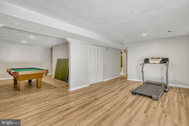 workout area with a textured ceiling, light hardwood / wood-style flooring, and billiards