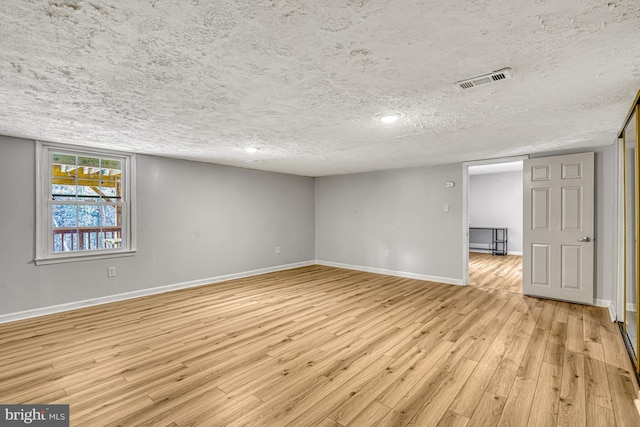 unfurnished room with a textured ceiling and light hardwood / wood-style flooring