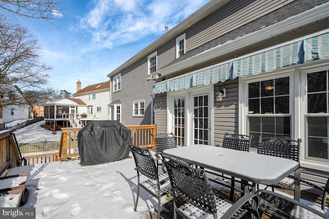 snow covered patio featuring a wooden deck, a grill, and french doors