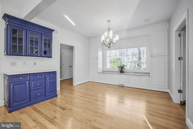 unfurnished dining area with light wood-type flooring and an inviting chandelier