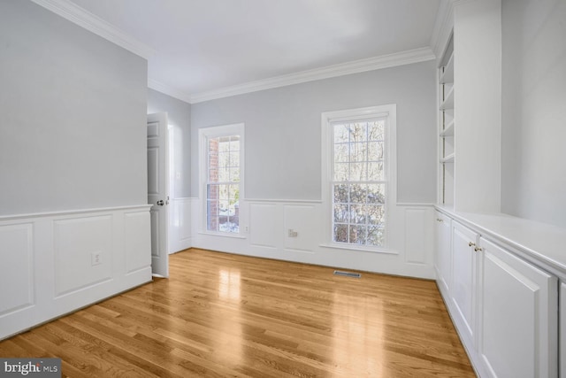 empty room featuring light hardwood / wood-style floors and crown molding