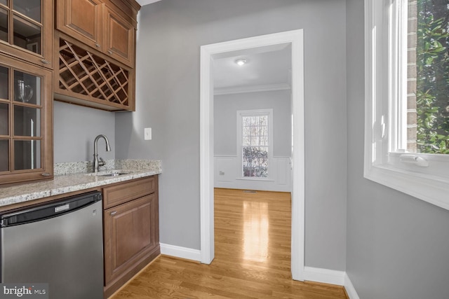 bar with plenty of natural light, light stone countertops, stainless steel dishwasher, and sink