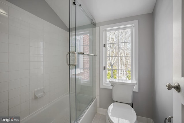 bathroom featuring toilet, bath / shower combo with glass door, vaulted ceiling, and plenty of natural light