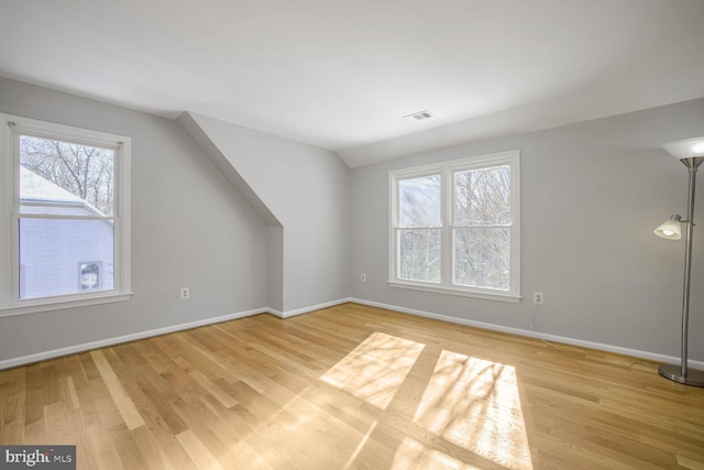 bonus room featuring vaulted ceiling, plenty of natural light, and light hardwood / wood-style flooring