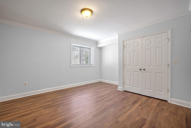 unfurnished bedroom with wood-type flooring, a closet, and crown molding