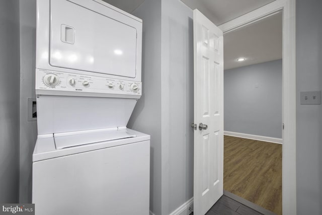 clothes washing area featuring stacked washer and dryer and dark hardwood / wood-style floors