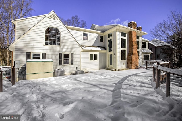 snow covered rear of property with central AC and a wooden deck