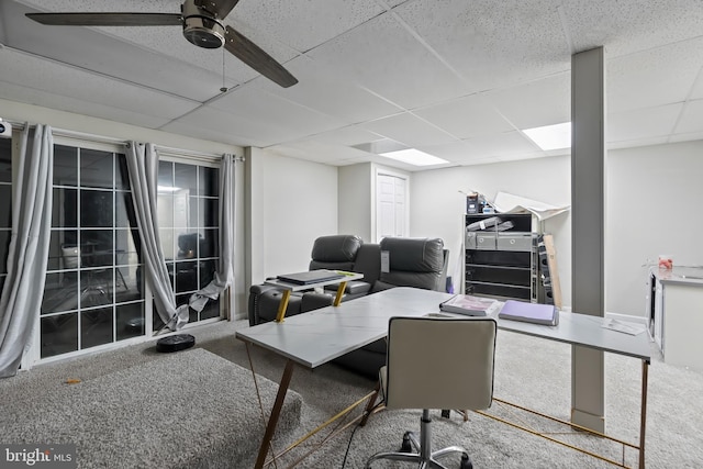 carpeted office space with a drop ceiling and ceiling fan