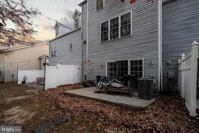 back house at dusk featuring a deck and central AC unit