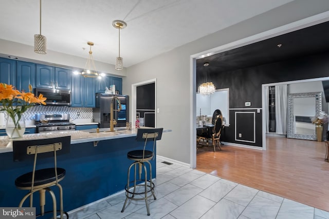 kitchen featuring appliances with stainless steel finishes, a kitchen breakfast bar, tasteful backsplash, blue cabinetry, and pendant lighting