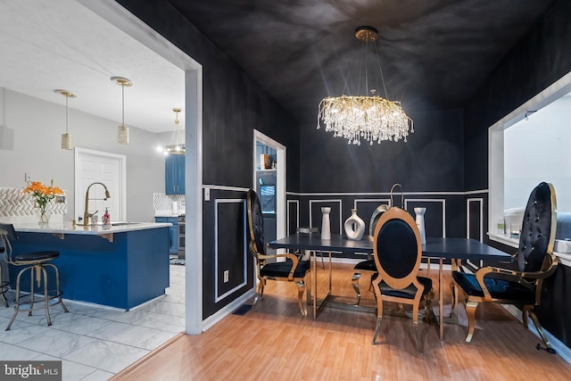 dining space featuring sink, a chandelier, and light wood-type flooring