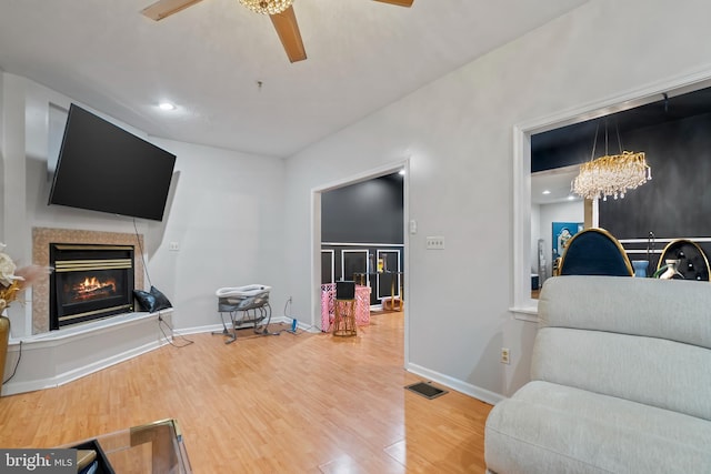 living room with wood-type flooring and ceiling fan with notable chandelier