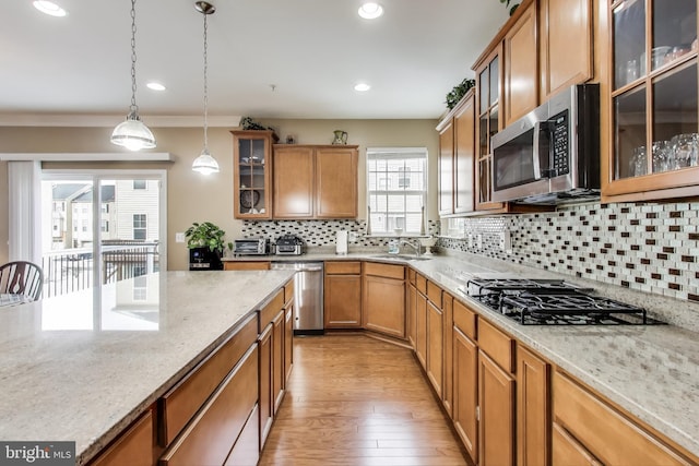 kitchen with crown molding, decorative light fixtures, sink, a wealth of natural light, and stainless steel appliances