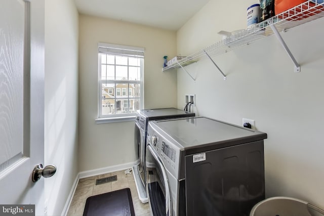 laundry room with independent washer and dryer and light tile patterned flooring