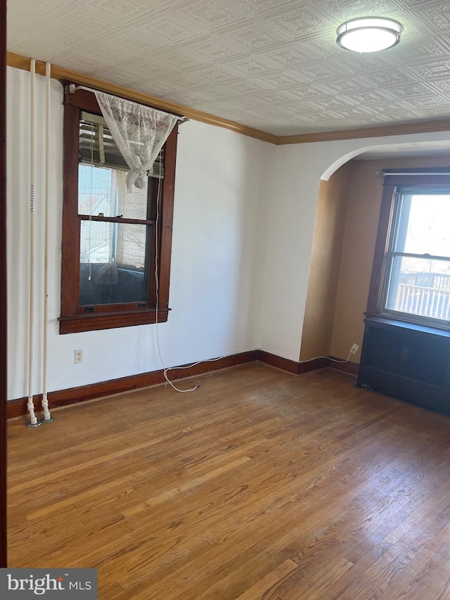 spare room featuring arched walkways, an ornate ceiling, and baseboards