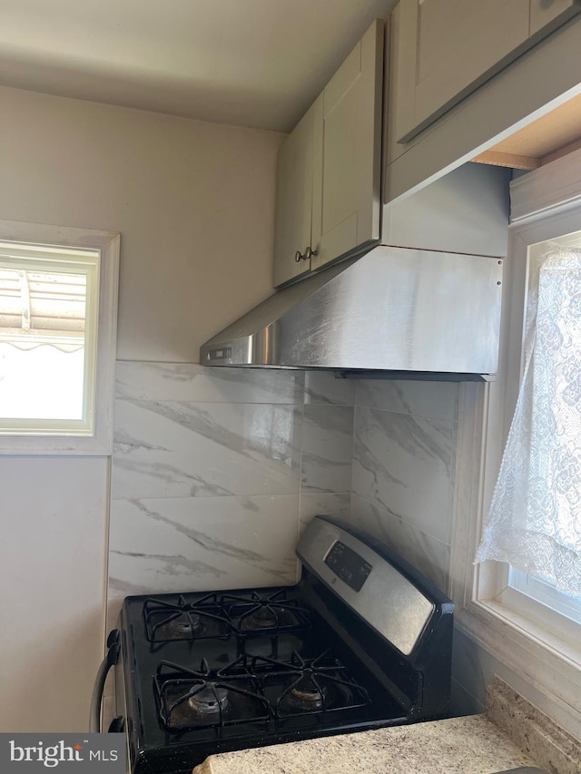 kitchen featuring under cabinet range hood and stainless steel gas range