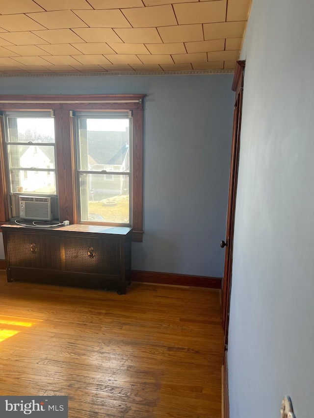 unfurnished room featuring cooling unit, baseboards, and wood finished floors