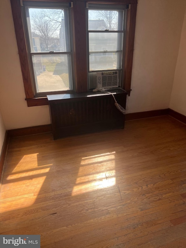 spare room featuring cooling unit, wood finished floors, and baseboards