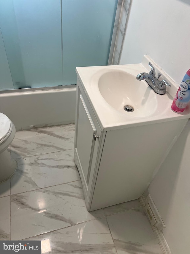 bathroom featuring toilet, marble finish floor, vanity, and  shower combination