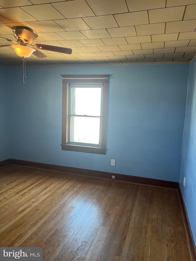 spare room with wood finished floors, baseboards, and ceiling fan