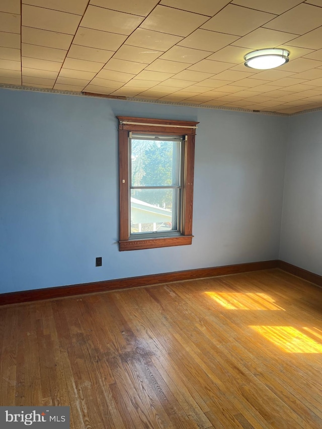 empty room with baseboards and hardwood / wood-style floors