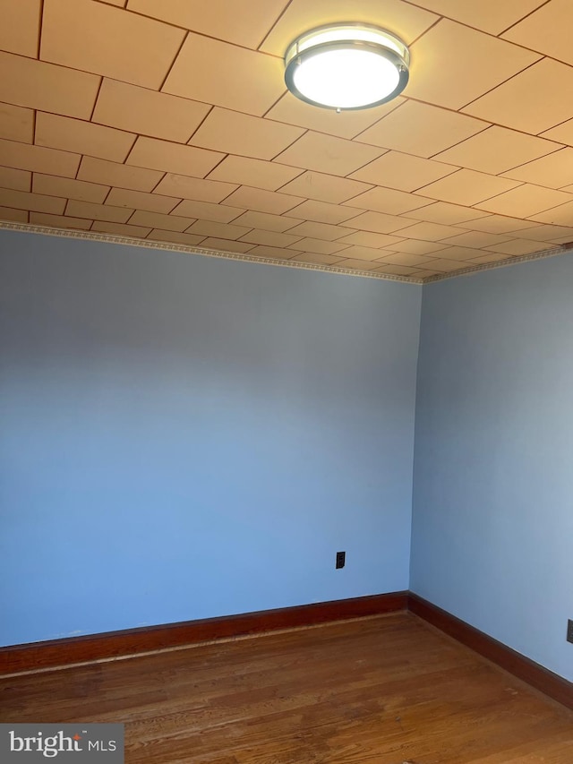 spare room featuring baseboards and wood finished floors