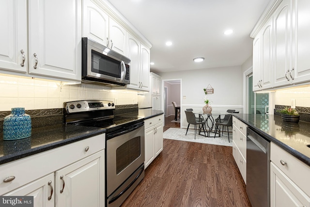 kitchen with dark stone countertops, white cabinetry, stainless steel appliances, dark hardwood / wood-style flooring, and decorative backsplash