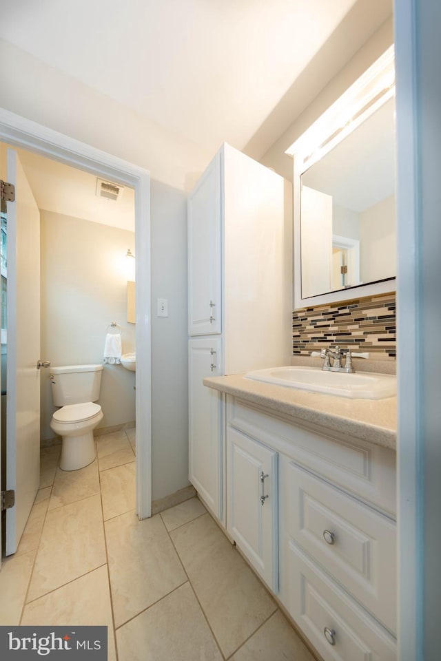 bathroom with vanity, tile patterned flooring, toilet, and backsplash