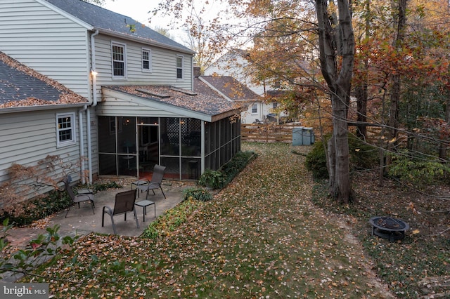 back of house featuring a patio, a sunroom, and a fire pit