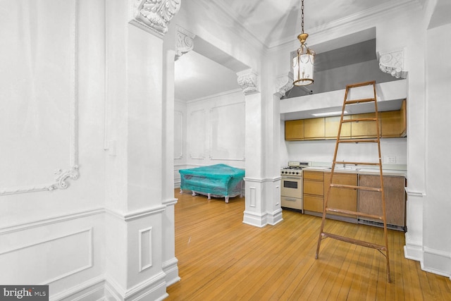 interior space with hardwood / wood-style flooring, high end stainless steel range oven, hanging light fixtures, and ornate columns